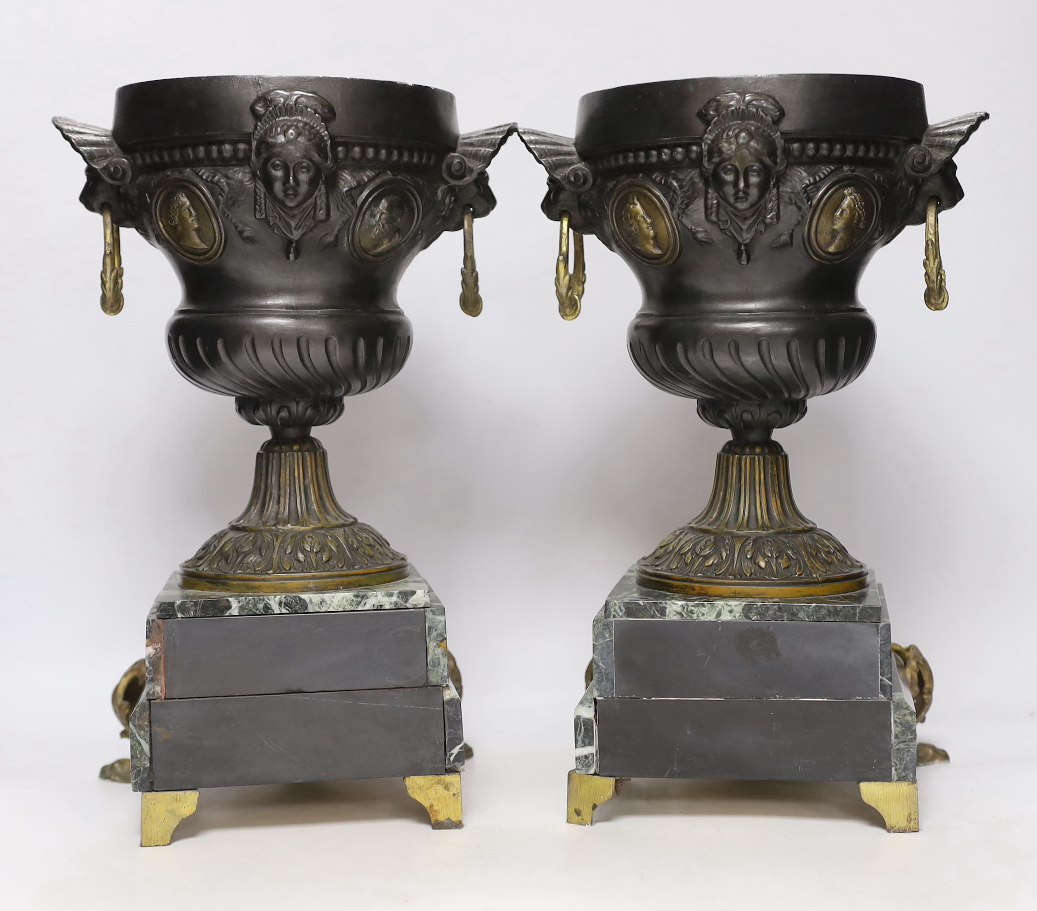 A pair of late 19th century French gilt metal and brown patinated urns, decorated with masks and serpentine plinths, 33cm high